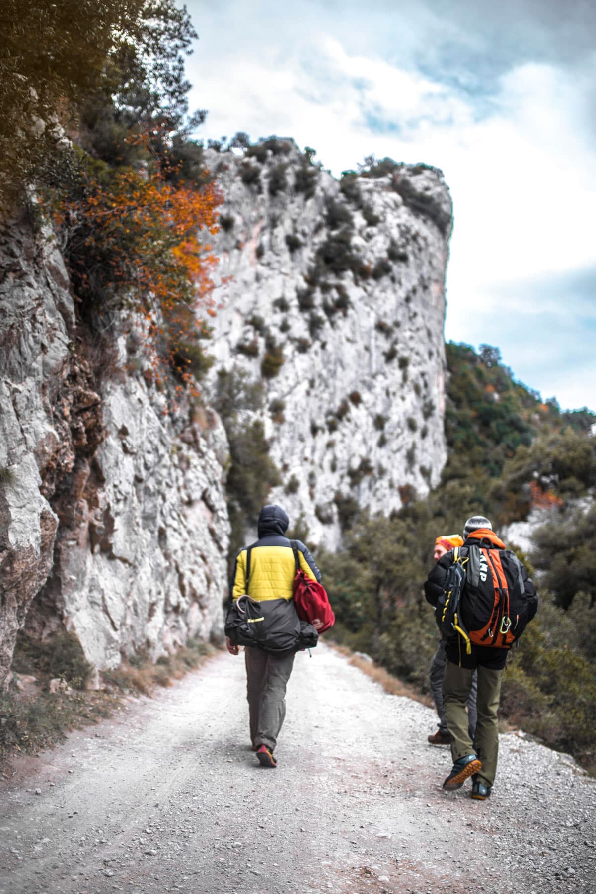 Escaladors caminant per la pista sota les parets de roca