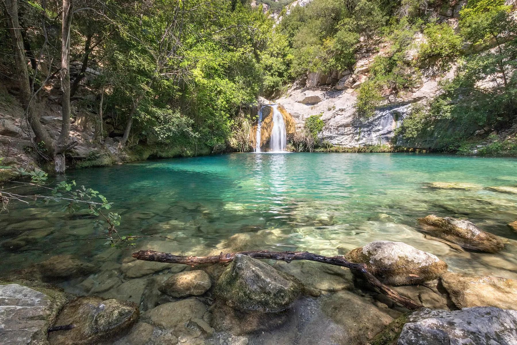 Un gorg d'aigua clara amb una petita cascada a Sadernes